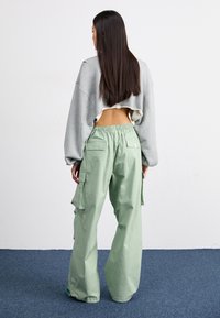 Afskåret grå sweatshirt med brede ærmer, parret med løse lysegrønne cargo-bukser med sidelommer og elastisk talje.