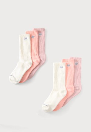 Tre par New Balance crew sokker i hvid, pink og lyse lilla, vist på en ensartet lys baggrund.