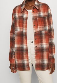 Rood-wit geruit overhemd van flanellen stof, met een knoopsluiting aan de voorkant, lange mouwen en een klassieke kraag met een ontspannen pasvorm.