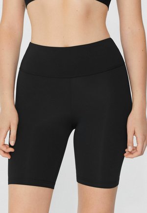 Black athletic shorts made from a smooth, stretch fabric with a high waistband and mid-thigh length, featuring minimal seam detailing.