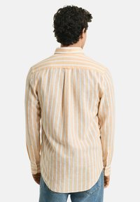 Gestreept T-shirt met lange mouwen van zachte stof, met verticale oranje en witte strepen, een button-down kraag en een gebogen zoom.