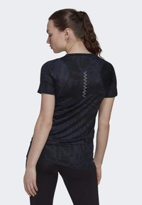 Camiseta atlética ajustada de manga corta en azul oscuro con un patrón texturizado y detalles de costura en zigzag en contraste a lo largo de la parte posterior.