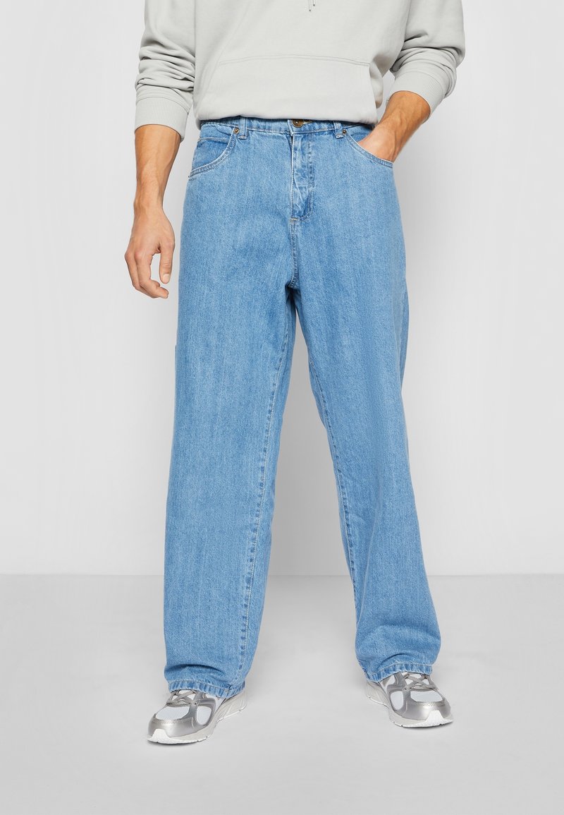 Vaaleansiniset farkut, leveälahkeinen malli, viisi-taskuinen tyyli, nappi- ja vetoketjukiinnitys, joissa on hienovarainen tekstuuri ja haalistunut pesu.