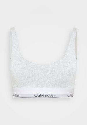Grijze cropped beha van zacht materiaal, met brede banden en een witte band met het logo "Calvin Klein". Soepele textuur en eenvoudig ontwerp.