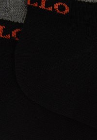 Calzini neri e grigi con texture a coste e dettagli del logo arancione a contrasto vicino alla cima. Materiale in maglia morbida.