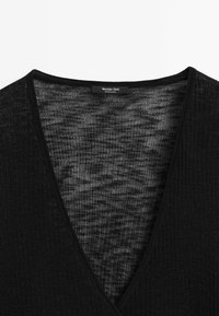 Schwarzer, gerippter V-Ausschnitt-Pullover aus Strick mit weicher Textur und tiefem Ausschnitt. Das Etikett trägt die Aufschrift "Massimo Dutti" und weist auf die Markenherkunft hin.