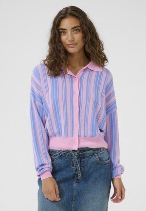 Różowo-niebieski sweter na guziki w paski z kołnierzem, z długimi rękawami i prążkowanym dołem. Spódnica jeansowa noszona poniżej talii.