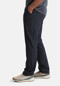 Pantalons navy à coupe décontractée, en tissu lisse. Dotés de poches latérales et d'une ceinture confortable. Assortis à des baskets beiges légères.