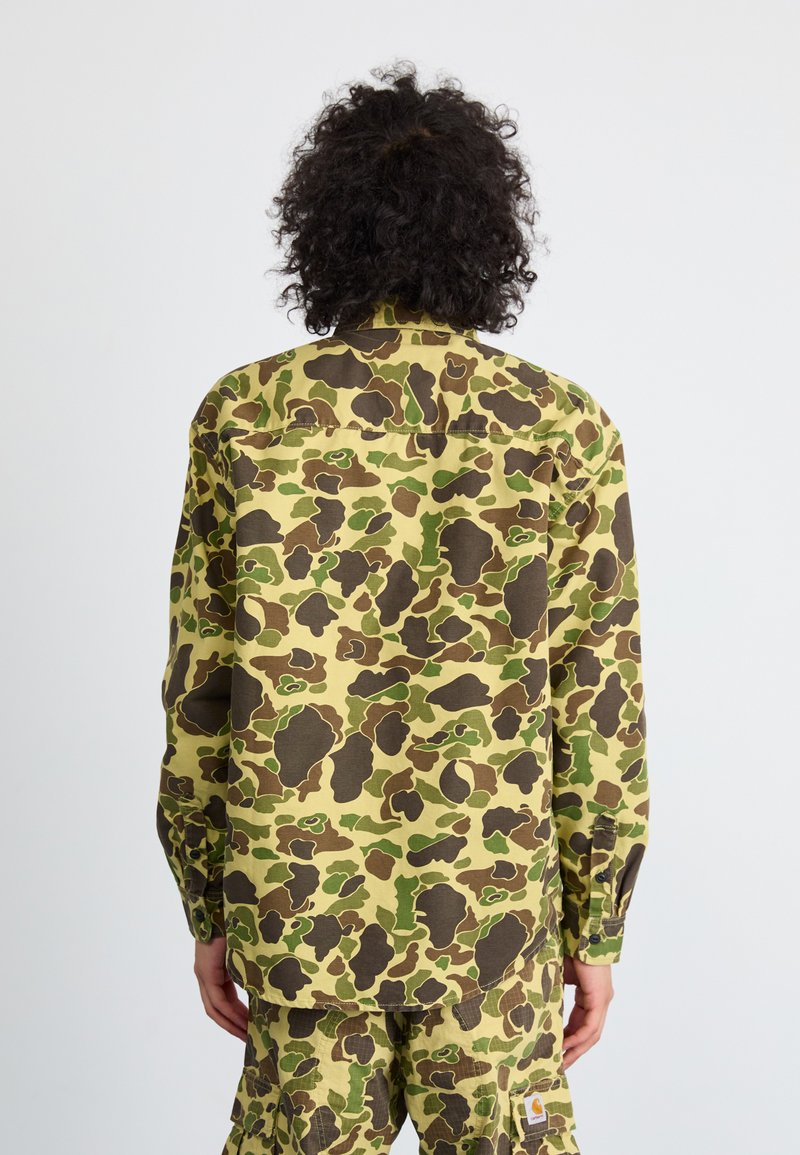 Langarmshirt in einem mehrfarbigen Tarnmuster mit Schattierungen von Grün und Braun, aus einem strapazierfähigen Stoff mit geknöpften Manschetten.