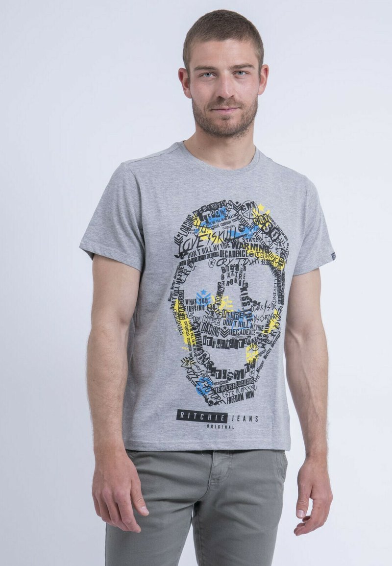T-shirt en coton gris avec un imprimé graphique d'un visage composé de texte en noir, jaune et bleu. Conçu avec un col rond et des manches courtes.