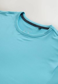 Camiseta deportiva de color azul brillante, fabricada con un tejido transpirable y texturizado, con cuello redondo y una pequeña etiqueta que indica la talla y la marca.