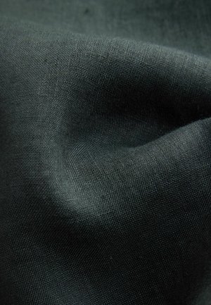 Gros plan sur un tissu gris foncé avec une texture tissée visible et des plis doux créant des ombres et des reflets subtils.