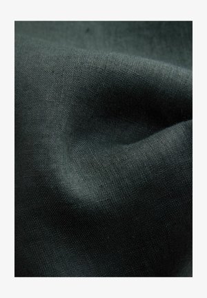 Gros plan sur un tissu gris foncé avec une texture tissée visible et des plis doux créant des ombres et des reflets subtils.