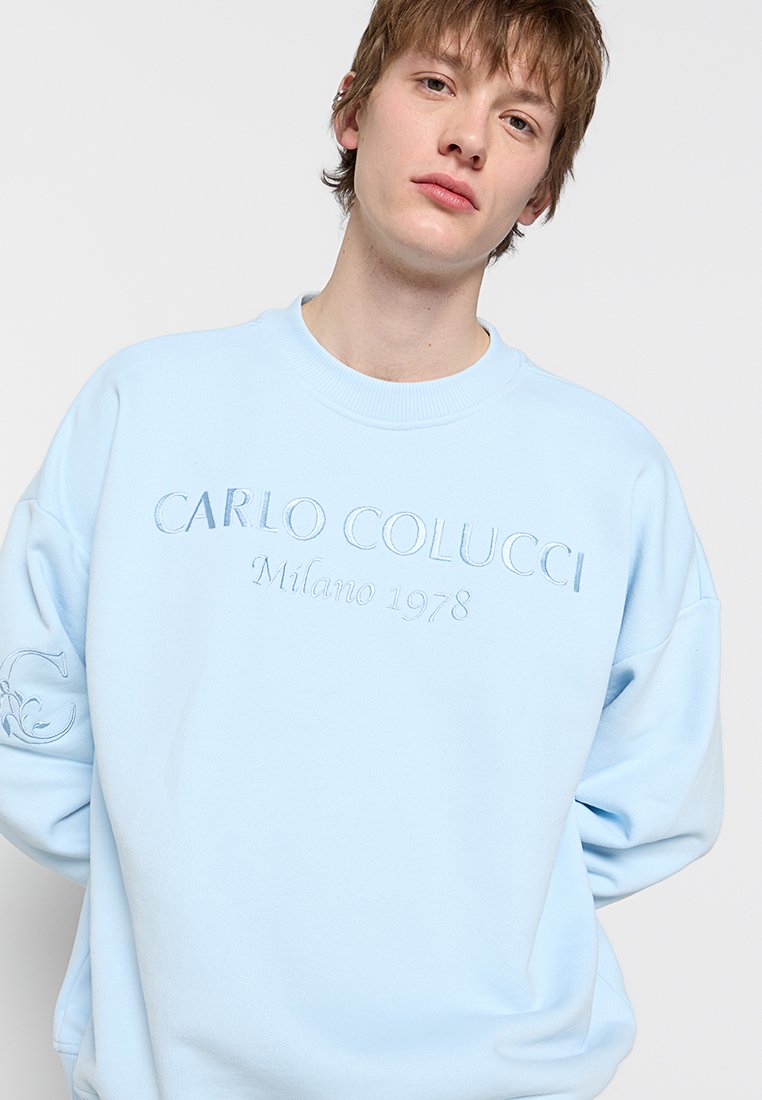 Lichtblauwe sweatshirt van zacht materiaal. Voorzien van reliëftekst "CARLO COLUCCI Milano 1978" op de voorkant en logodetail op de mouw.