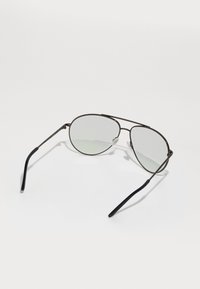 Óculos de sol aviador em metal com tintura cinza. Têm hastes finas em preto e um design elegante e minimalista. Apresentam almofadas de nariz ajustáveis para maior conforto.