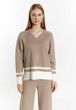 Beige pletený svetr s výstřihem do V, kontrastními bílými pruhy na lemech a manžetách a volným střihem. Hladká textura a dlouhé rukávy.