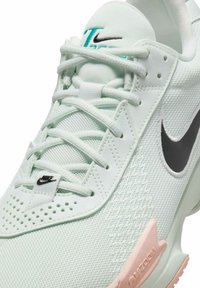 Baskets vert menthe clair avec tige en mesh, swoosh noir de Nike, lacets blancs et accent rose sur la semelle ; design perforé pour la ventilation.