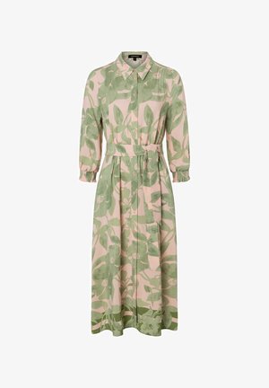 Langes Hemdkleid auf pinkem Hintergrund mit grünen Blattmustern, mit Kragen, Knopfverschluss und bindbarem Taillenzug. Mit elastischen, gerafften Ärmeln.