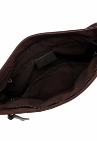 Dunkelbraunes Stofftaschen-Innere mit einem Reißverschlusstasche und einem offenen Fach, von oben gezeigt, wobei der Reißverschluss teilweise geöffnet ist.