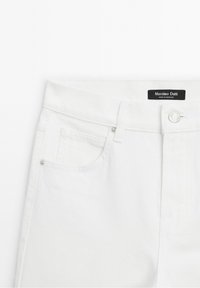 White denim jeans featuring a button closure, a front pocket, and a branded label on the waistband. Smooth texture with a classic fit.