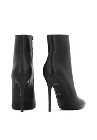 Botines negros de cuero con tacones altos, acabado liso, cierre de cremallera y tacones stilettos finos, con puntera redondeada y diseño elegante.