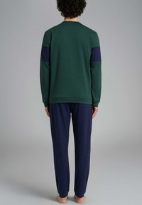 Felpa verde con dettagli blu navy, scollatura rotonda e maniche lunghe abbinata a pantaloni blu scuro dalla vestibilità comoda e realizzati in tessuto morbido.