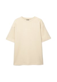 Beige oversized t-shirt med korte ærmer lavet af blødt stof. Har en rund halsudskæring og en lille tekstdetalje på forsiden.