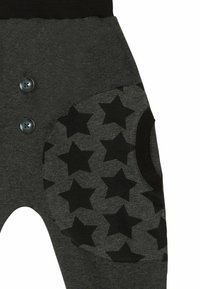 Pantaloni di cotone grigi con una vita a costine, caratterizzati da tasche con motivo a stelle nere e due bottoni scuri sul lato anteriore.