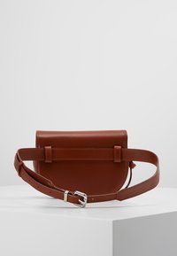 Bolso bandolera de cuero marrón con textura suave, forma rectangular y correa ajustable. Tiene un cierre con solapa y acentos de hardware mínimos.