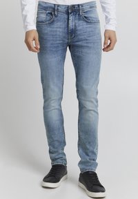 Ljusblå slim-fit jeans i denimtyg med blekta områden. Har fem fickor, kontrasterande sömmar och knappgylf.