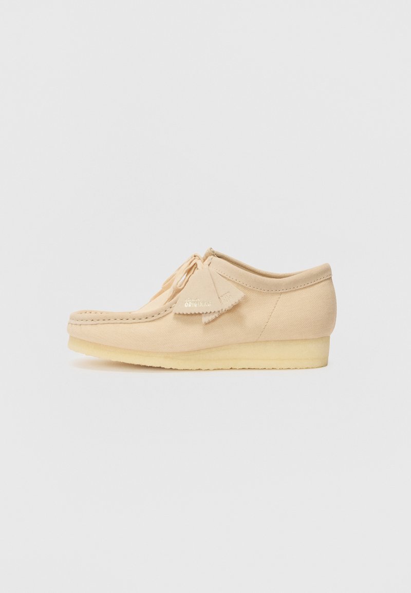 Scarpe in tela beige con un design a mocassino cucito, dettagli frangiati e suola bassa e resistente per comfort e flessibilità.