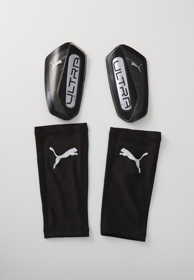 Zwarte voetbalscheenbeschermers met het label "ULTRA Flex" en metalen accenten, gecombineerd met zwarte stoffen mouwen die voorzien zijn van een wit Puma-logo.