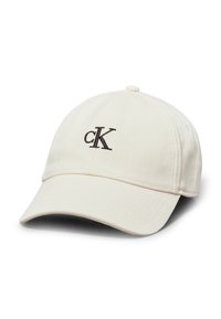 Cotton cap in cream with a curved brim. Features a brown embroidered "cK" logo on the front. Classic six-panel design with stitching details.