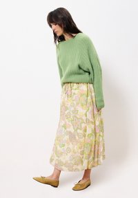 Lichtgroen geribbeld truitje, bloemen pastel maxi rok met roze en gele patronen, en lichtbruine ballerina's met een strik.