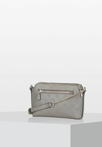 Harmaa olkalaukku, jossa on kohokuvioidut kukkakuviot, hopeinen vetoketjupussi ja koristeellinen hopeaketjusäilytys valkoisella pedestaalilla.