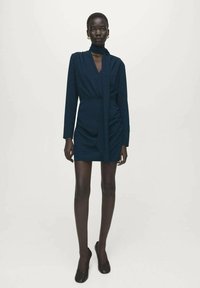 Marineblauwe wikkeljurk met een hoge kraag en lange mouwen, met geplooide details bij de taille en een gladde, licht gestructureerde stof.