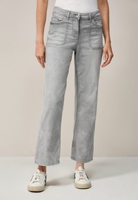 Grijze denim high-waisted jeans met zakken, rechte pijpen, lichte wassing en minimale stikdetails, gecombineerd met witte sneakers.
