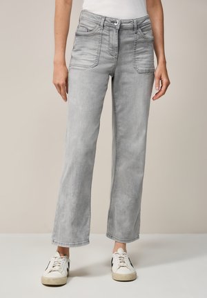 Jean en denim gris taille haute avec poches, design à jambes droites, délavé léger et détails de couture minimalistes, associés à des baskets blanches.