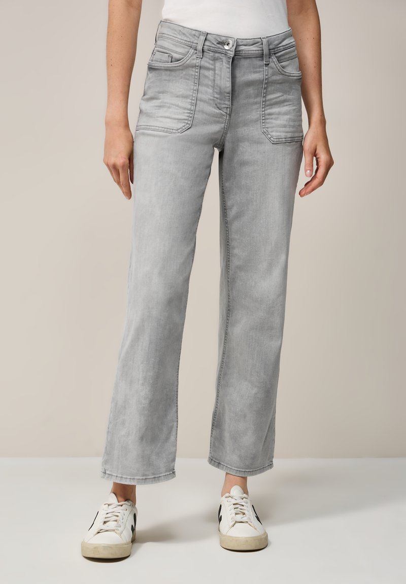 Grijze denim high-waisted jeans met zakken, rechte pijpen, lichte wassing en minimale stikdetails, gecombineerd met witte sneakers.