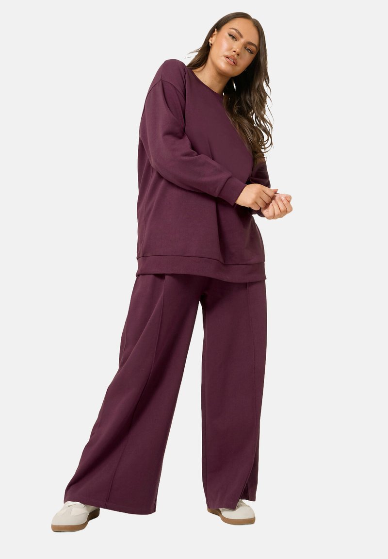 Lila oversized sweatshirt och matchande vidbyxor i mjukt tyg, med en avslappnad passform och minimala sömdetaljer.