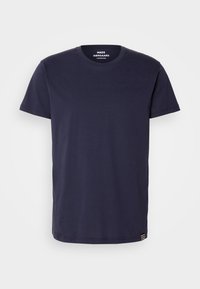 T-shirt en coton bleu marine avec un col rond et des manches courtes. Présente une petite bande d'emblème en bas et une texture lisse.