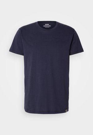 Marineblå bomull T-skjorte med rund hals og korte ermer. Har en liten emblemstripe ved kanten og en jevn tekstur.