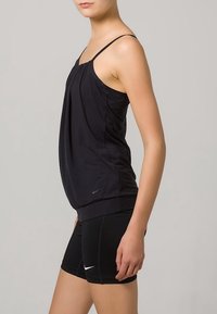 Sort atletisk tanktop med tynde stropper, samlet design og en tætsiddende talje, parret med sorte shorts med et hvidt Nike-logo.