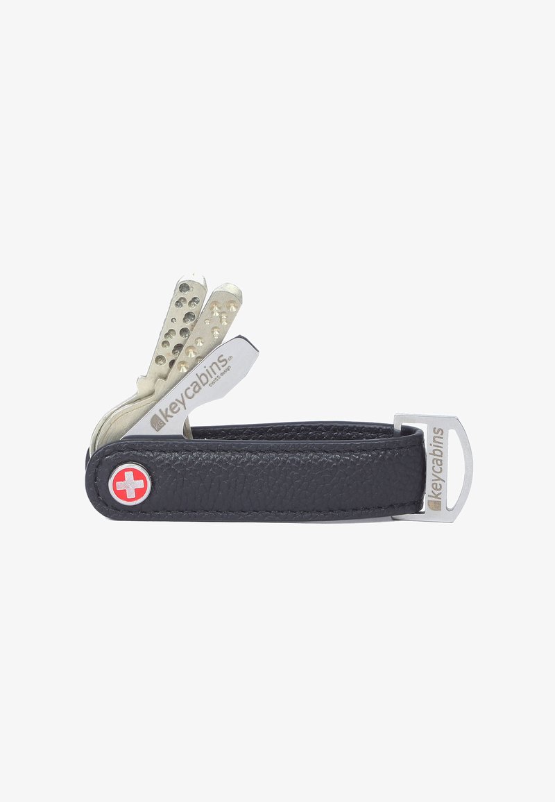 Organisateur de clés compact avec un corps en cuir noir, des accessoires en métal argenté, plusieurs emplacements pour clés et un emblème rouge de croix suisse.