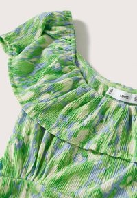 Tissu à motifs verts et bleus avec un col froncé et un matériau texturé plissé sur un vêtement.