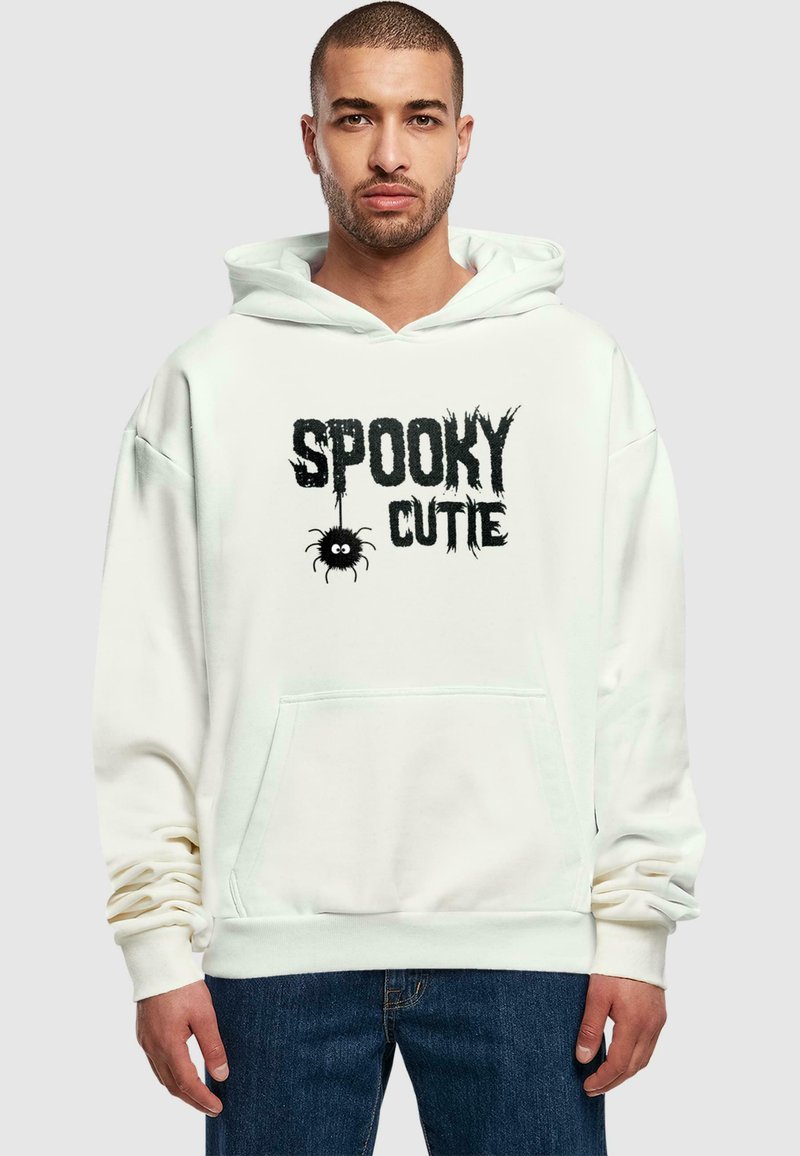 Valge kapuutsiga särk, mis on valmistatud pehmest kangast, koos musta "Spooky Cutie" graafikaga, millel on ämbliku detail. Sisaldab känguru taskut ja soonikutega mansette.