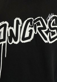 Black t-shirt featuring bold white graffiti-style text reading "ANGRS" with drips and an accent mark. Soft cotton material, standard fit.