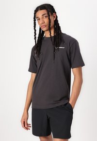 Dark gray short-sleeved t-shirt made of cotton blend fabric, featuring a simple crew neck and a small white logo on the chest.