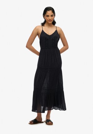 Zwarte mouwloze maxi-jurk met een getailleerde bovenkant, kantdetails en meerdere lagen rok. Heeft verstelbare bandjes en een lichtgewicht stof.