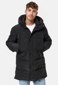 Chaqueta de plumas negra con un cuello alto, cierre de botones y cremallera, bolsillos delanteros y un acabado texturizado. Cuenta con una capucha y un diseño acolchado.
